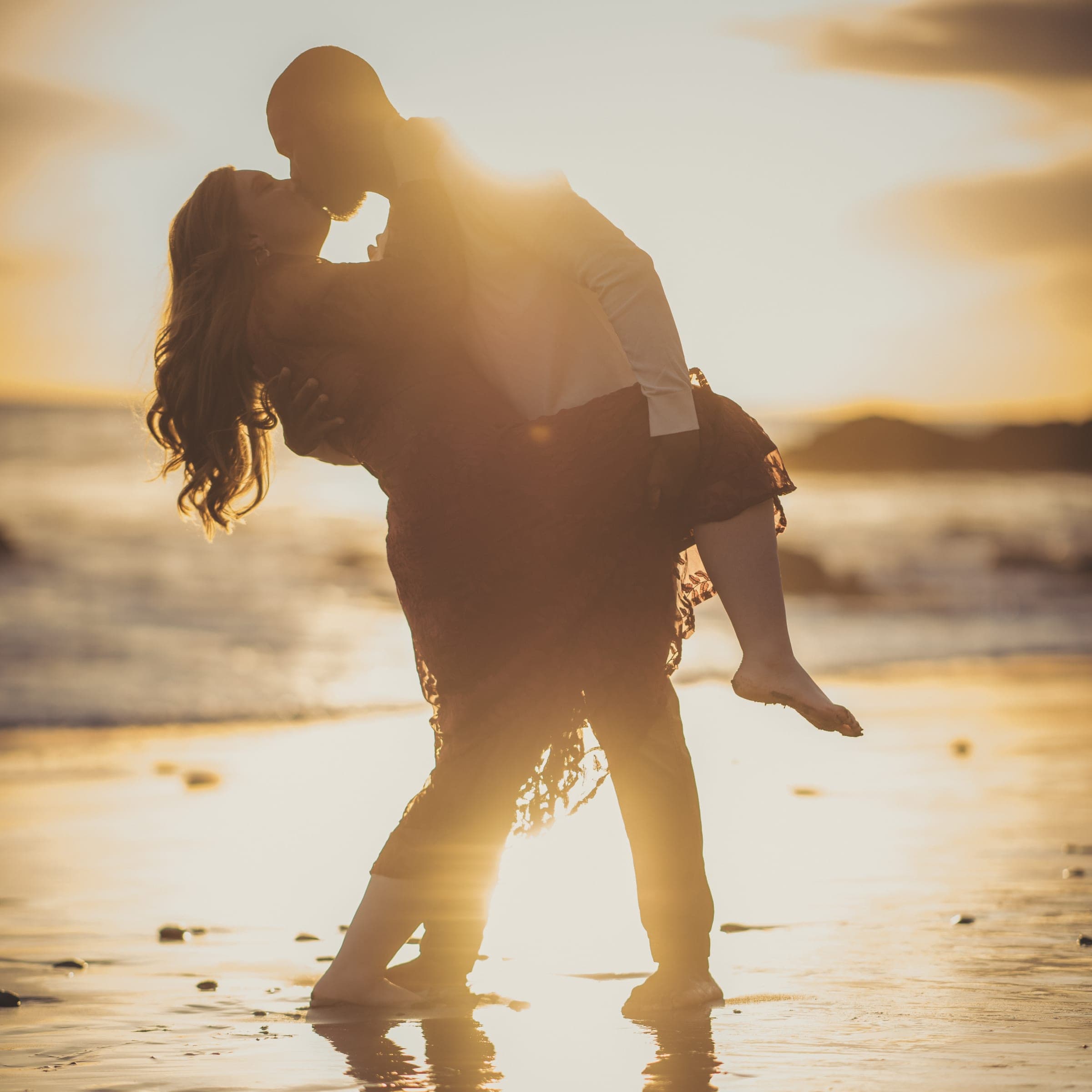Engagement couple dip on the beach at sunset