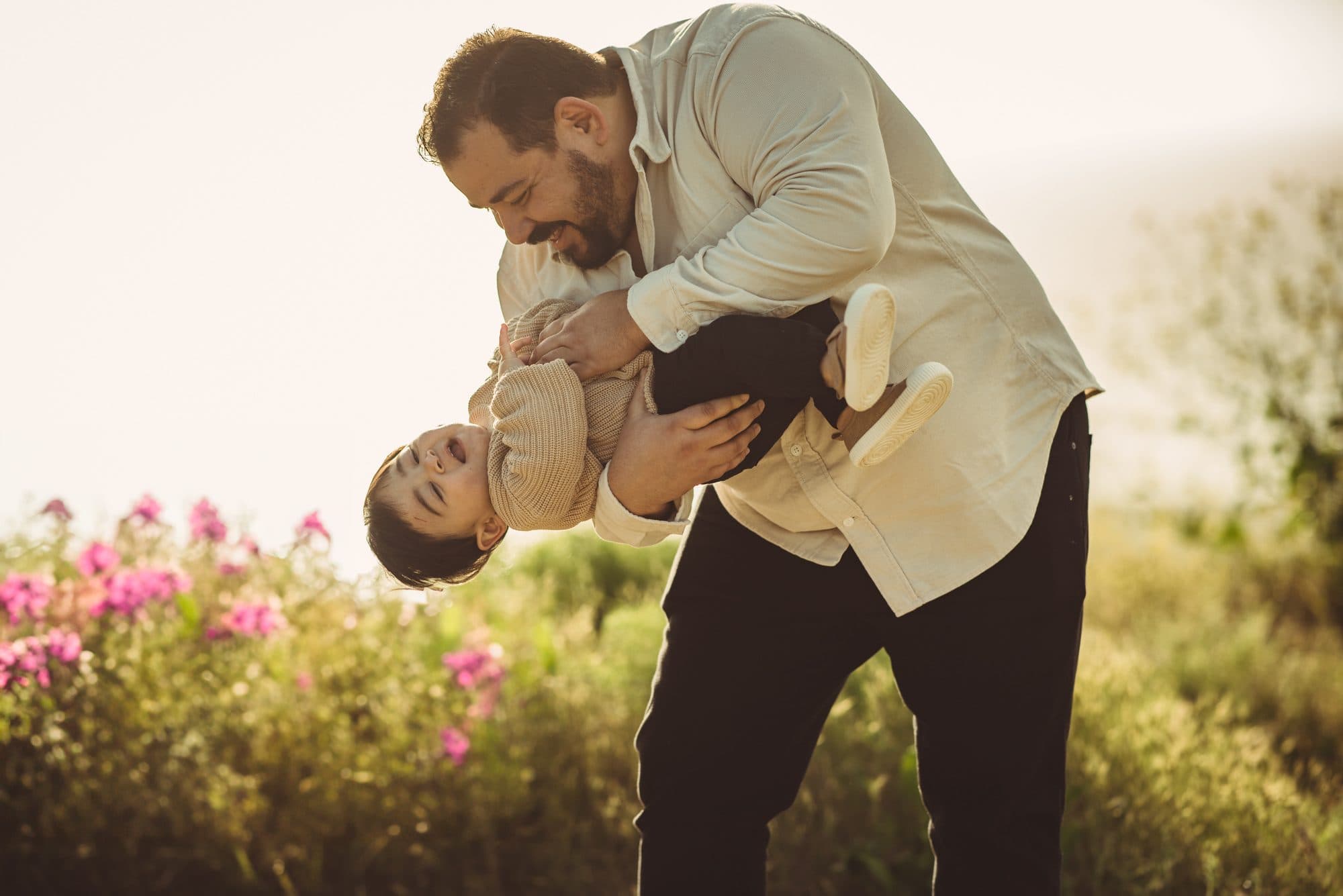 Father lifting his baby in a golden wildflower field