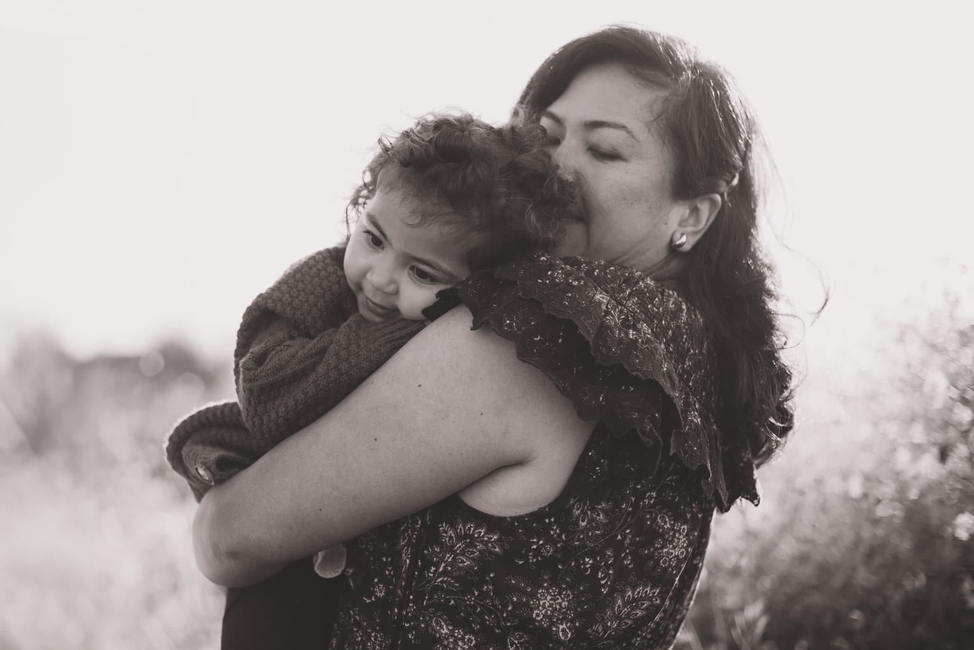 Mother kissing her child at golden hour, black and white