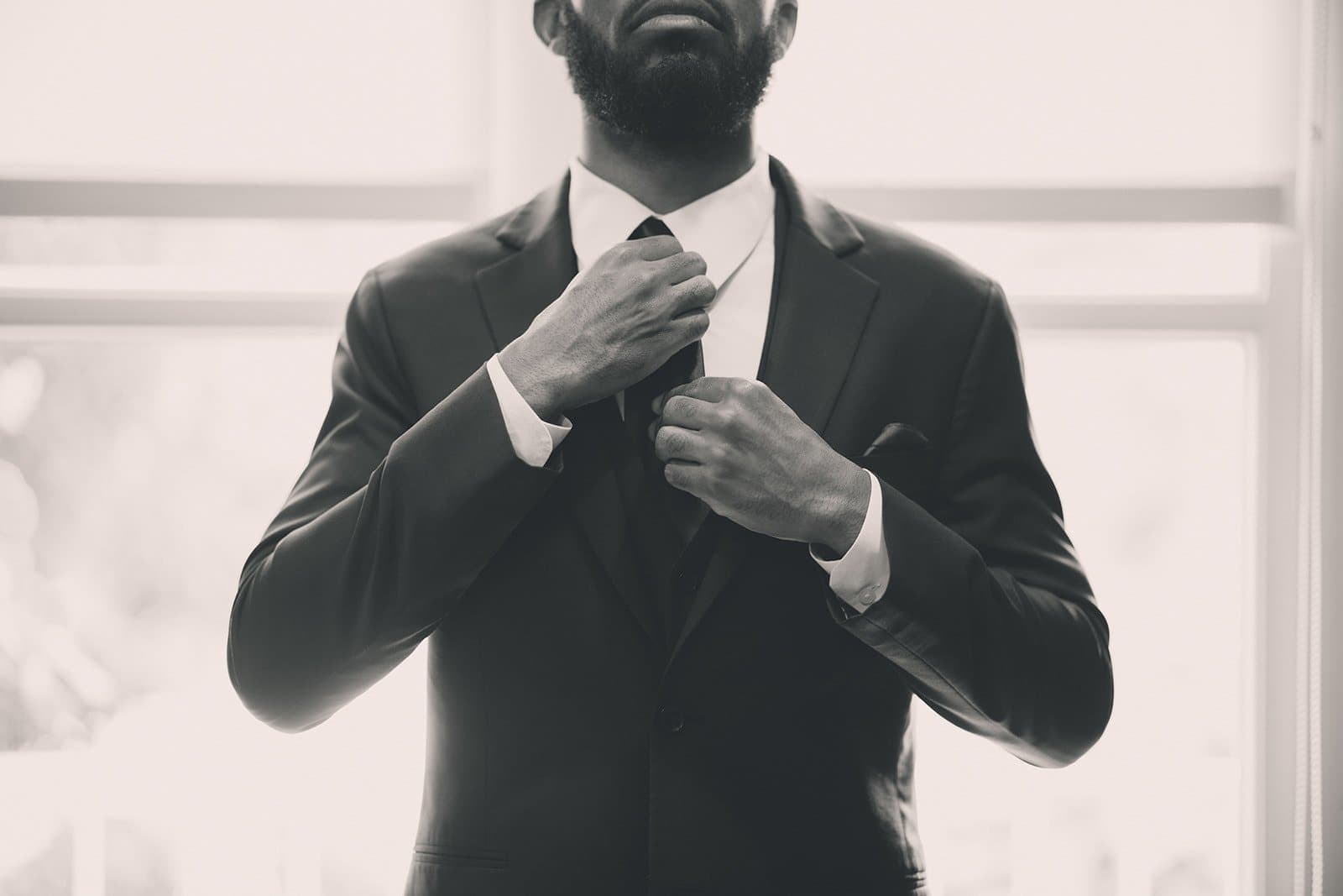 Groom straightening his tie, black and white