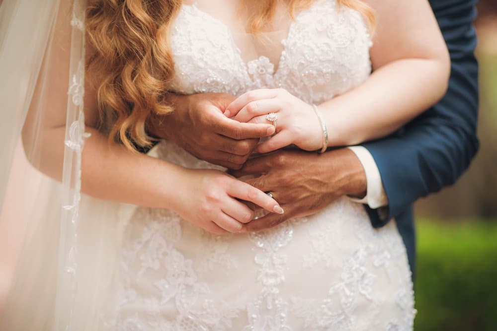 Bride and groom hands with engagement ring